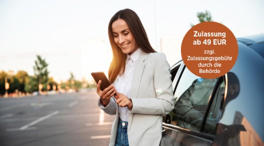 Eine Frau lehnt sich entspannt an ihr Auto an, während sie auf ihr Handy schaut.