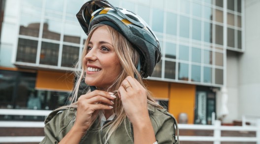 Eine Frau setzt sich einen Helm auf und lächelt dabei