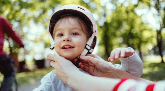 Ein Kind bekommt einen Helm aufgesetzt Ein Kind bekommt einen Helm aufgesetzt
