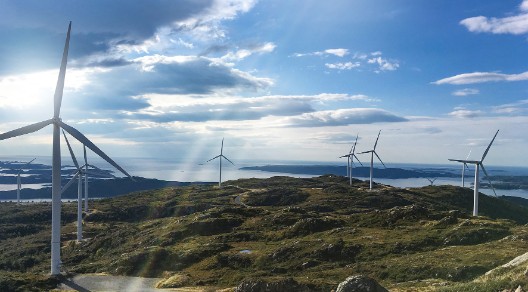 Windräder in Landschaft mit Sonnenschein und leicht bewölktem Himmel
