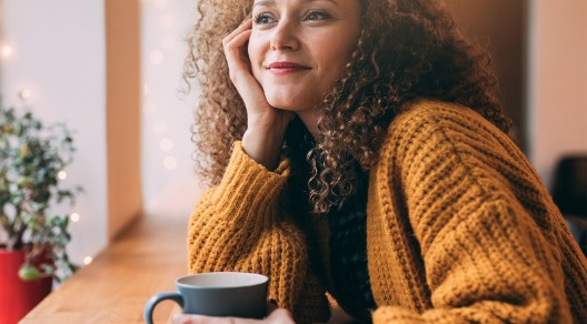 Junge Frau in Gedanken, hält Tasse in der Hand