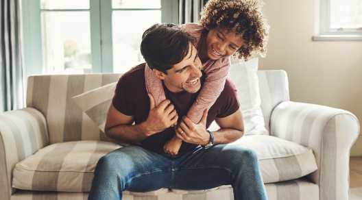 Vater und Kind tollen zuhause auf dem Sofa