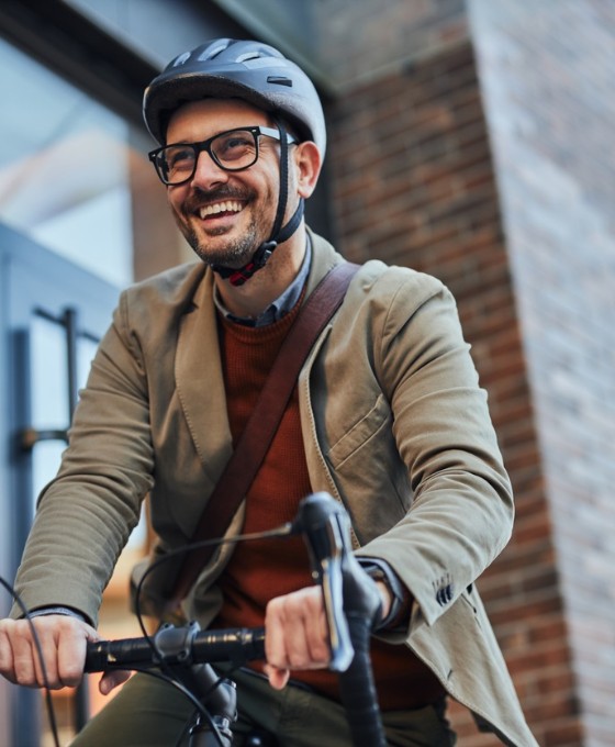 Ein Mann im Sacko mit Helm fährt mit seinem Fahrrad los.