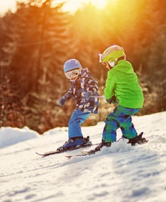 Zwei kleine Kinder mit ihren Skiern auf der Skipiste.