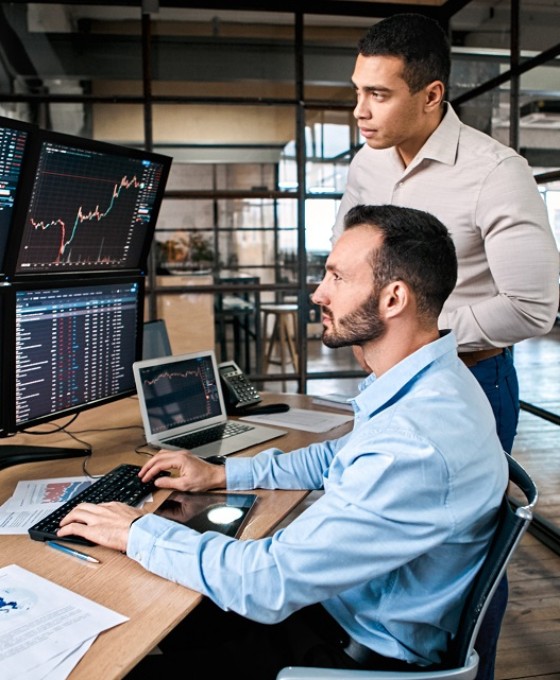 Zwei Männer sind im Büro und schauen zusammen auf einen Computerbildschirm.