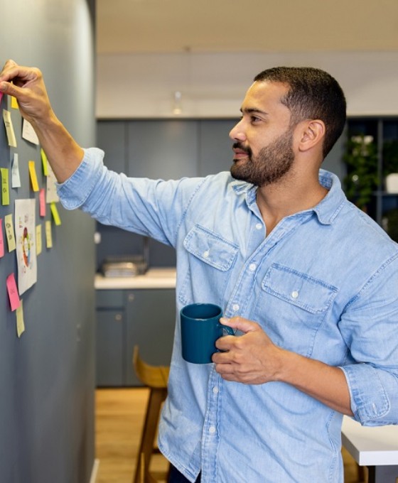 Ein junger Büroangestellter sortiert Post-its an einem Flipboard