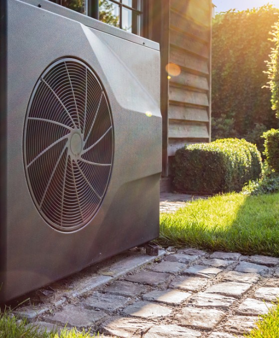 Eine im Garten stehende Wärmepumpe bei Sonnenlicht.