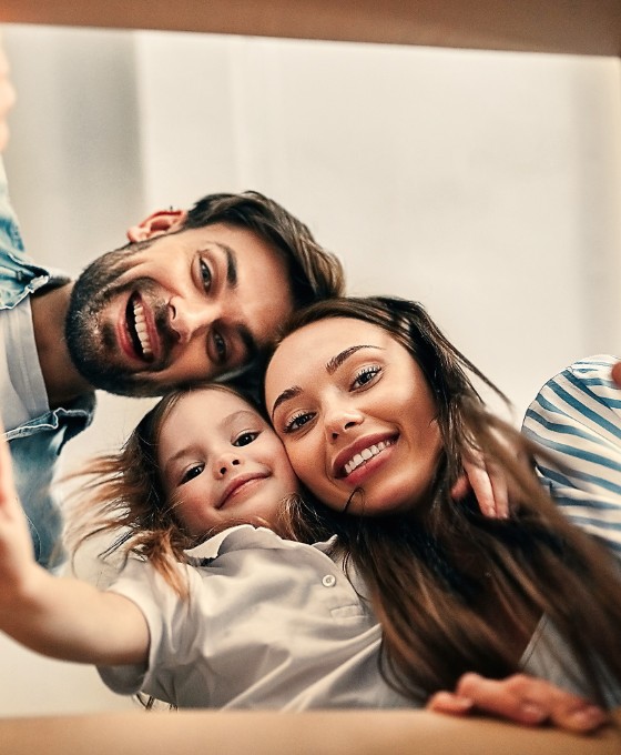 Eine lachende Familie sieht von oben in einen Karton