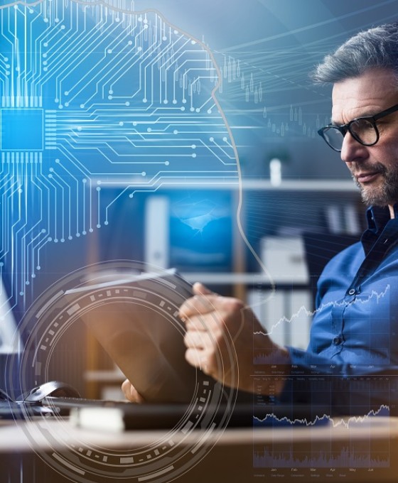 Ein Business-Mann sitzt arbeitend vor seinem Computer am Tablet im Büro. 