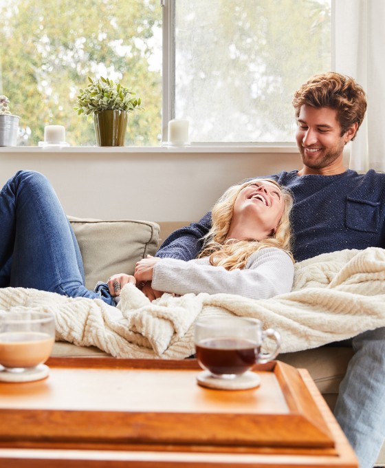 Ein Mann und eine Frau sitzen entspannt zuhause auf ihrem Sofa