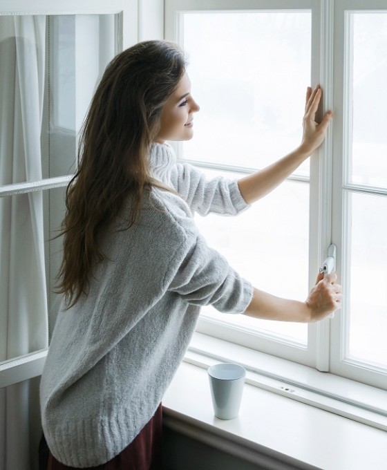 Eine Frau schließt ein Fenster von Innen.