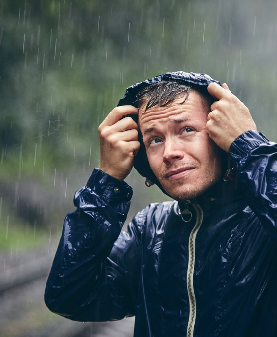 Ein Mann hat seine Kapuze auf, um sich vor dem starken Regen zu schützen.