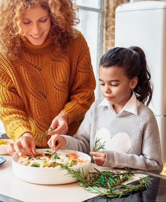 Eine Mutter macht  mit ihrer Tochter einen Auflauf in der Küche zusammen. 