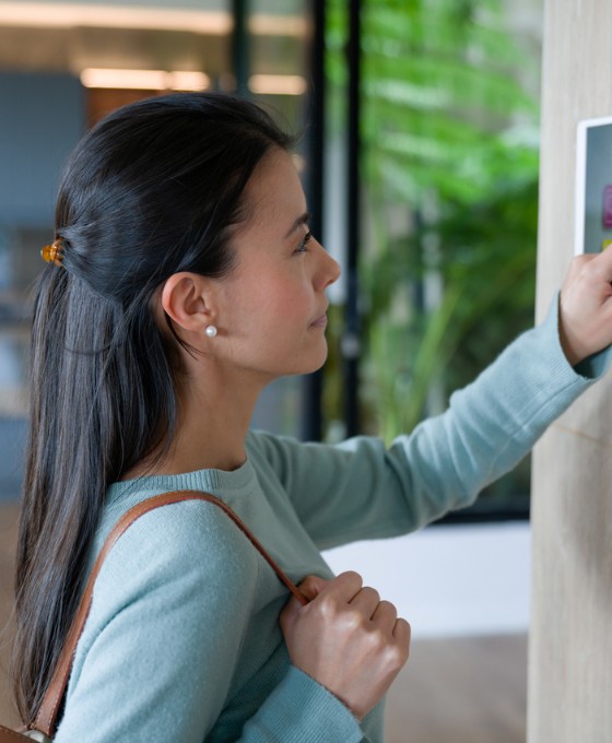 Frau verlässt ihr Haus und schließt die Tür mit einem automatisierten Sicherheitssystem ab.