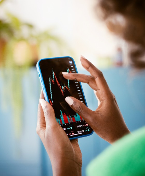 Frau zoomt mit den Fingern näher an eine Aktien-Grafik auf ihrem Handy.