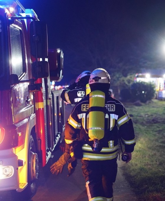 Feuerwehrmänner gehen entlang Feuerwehrauto zum Einsatz abends.