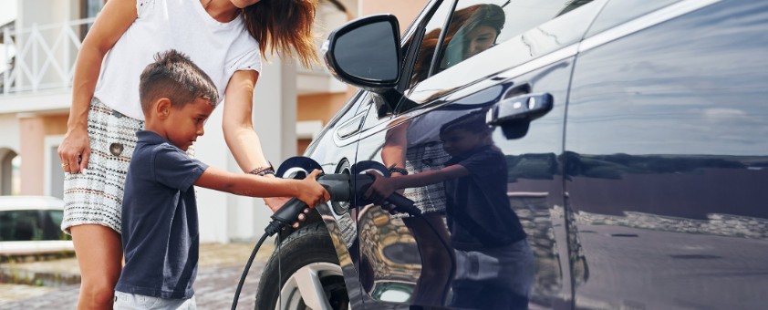 Eine Mutter und ihr kleiner Sohn schließen gemeinsam ihr Auto an die Ladesäule an