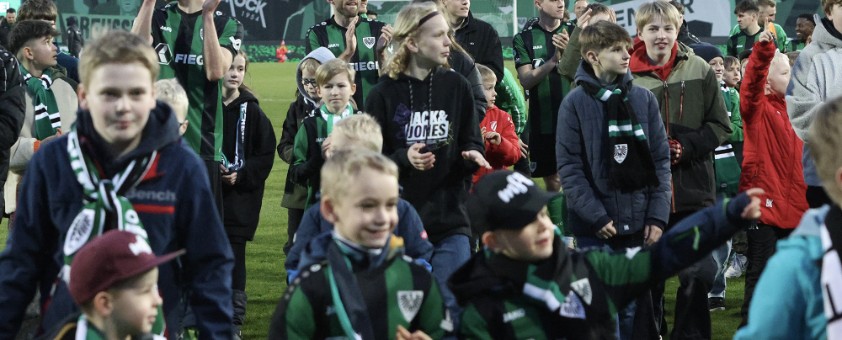 Mehrere Kinder und einige Spieler des Fußballvereins Preußen Münster. 