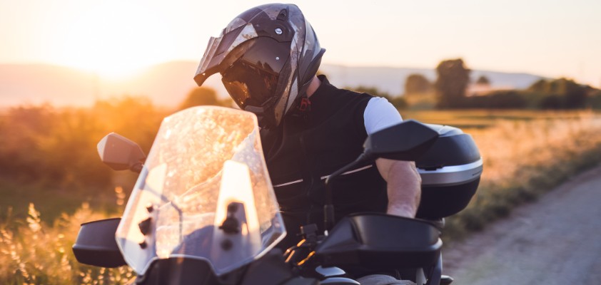 Motorradfahrer macht während einer Fahrt auf der Landstraße bei Sonnenuntergang eine Pause.
