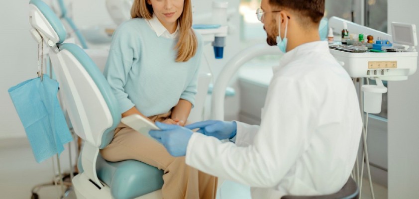 Patientin sitzt im Behandlungsstuhl beim Zahnarzt und bespricht Kostenplan 