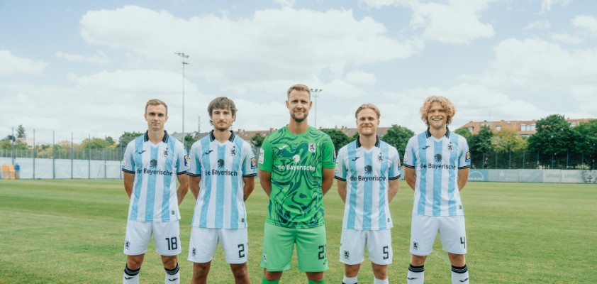 Mehrere Spieler des TSV 1860 München haben sich mit hinter dem Rücken verschränkten Armen aufgestellt