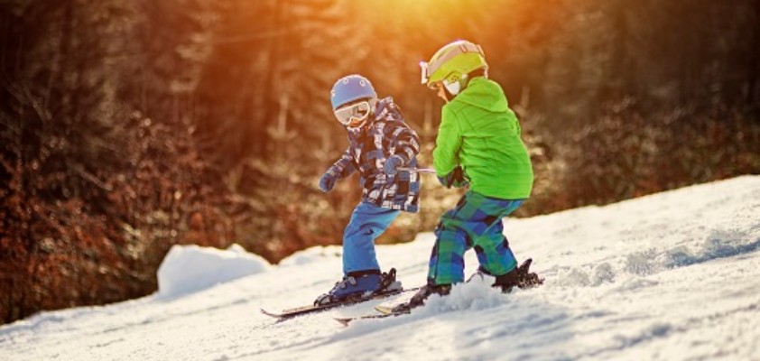 Zwei kleine Kinder mit ihren Skiern auf der Skipiste.