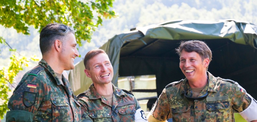 Drei junge, männliche Bundeswehr-Soldaten unterhalten sich lachend. Sie tragen alle Uniform. 