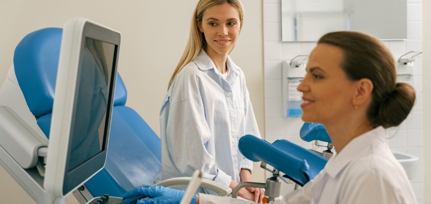 Patientin beim Gynäkologen, Ärztin bereitet eine Untersuchung im Behandlungsraum vor.