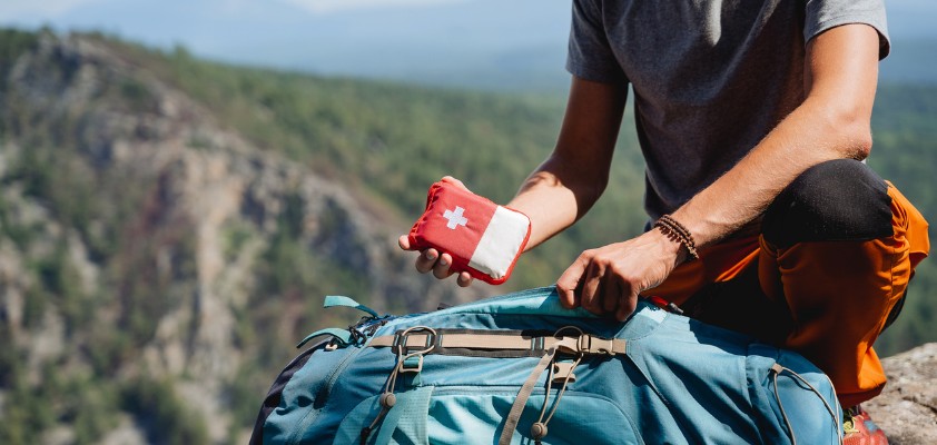 Ein Mann verstaut einen Erste-Hilfe-Kasten in seinem Rucksack.
