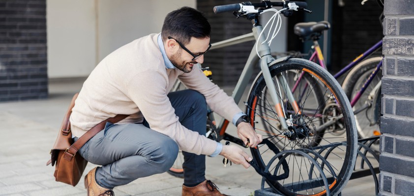 Ein Mann schließt sein Fahrrad auf der Straße ab.
