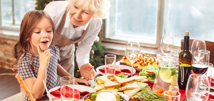 Eine ältere Dame und ein junges Mädchen stehen gemeinsam an einem Weihnachtsbuffet.
