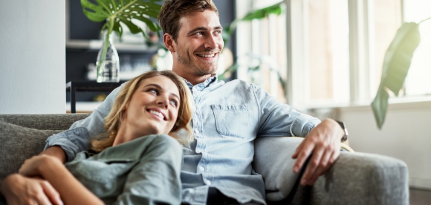 Mann und Frau sitzen gemütlich gemeinsam auf der Couch