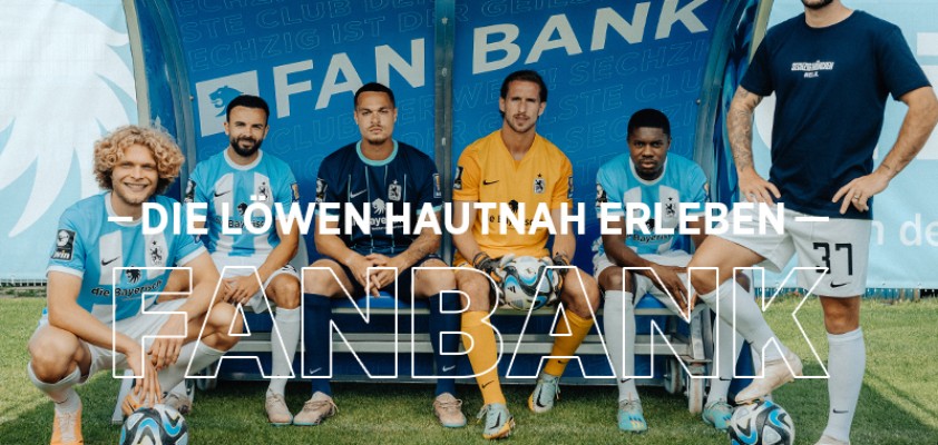 Mehrere Spieler des TSV 1860 auf einer Bank am Spielfeldrand mit Schriftzug "Fanbank"