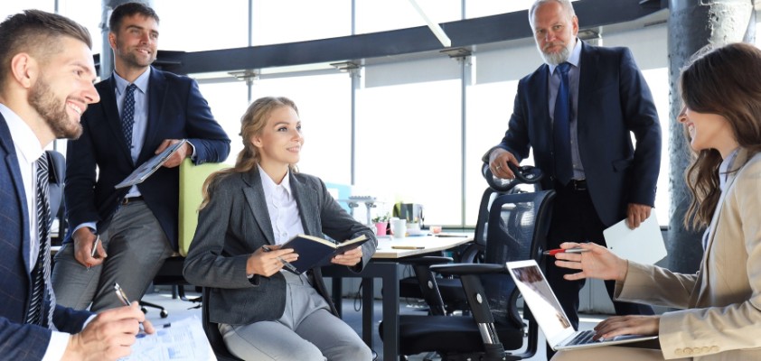 Fünfköpfiges Team bespricht sich in einem hellem Bürogebäude