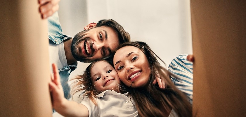 Eine lachende Familie sieht von oben in einen Karton