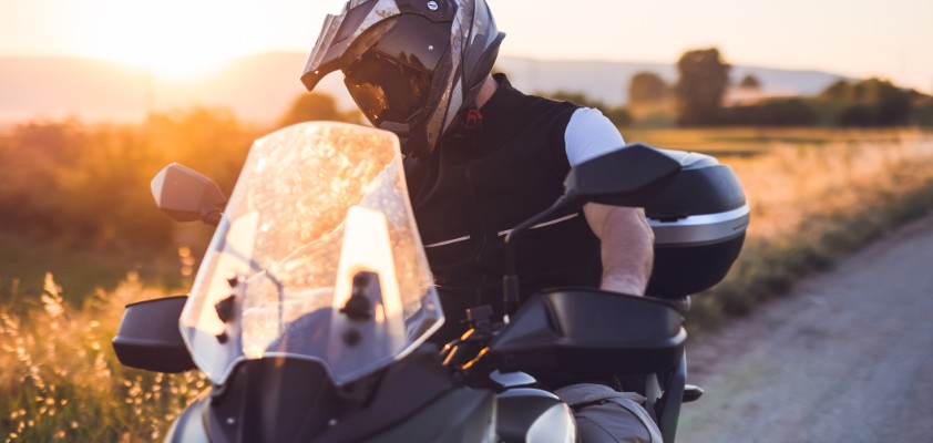 Motorradfahrer macht während einer Fahrt auf der Landstraße bei Sonnenuntergang eine Pause.