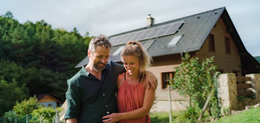 Mann und Frau stehen Arm in Arm im Garten eines Einfamilienhauses