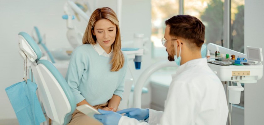 Patientin sitzt im Behandlungsstuhl beim Zahnarzt und bespricht Kostenplan 