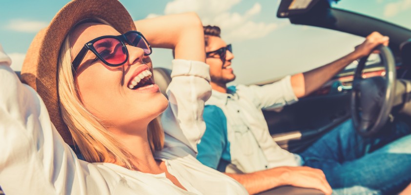 Eine Frau und  ein Mann sitzen zusammen im Cabrio und genießen das sonnige Wetter. 