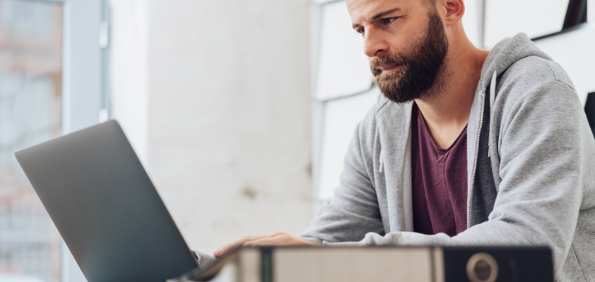 Ein Mann sitzt an seinem Laptop.
