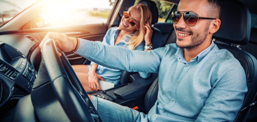 Junges Pärchen sitzt zusammen im Auto, während der Mann fährt