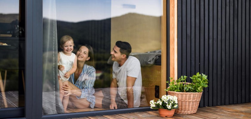 Eine Familie schaut lächelnd aus dem Fenster.