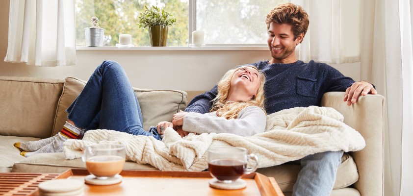 Ein Mann und eine Frau sitzen entspannt zuhause auf ihrem Sofa