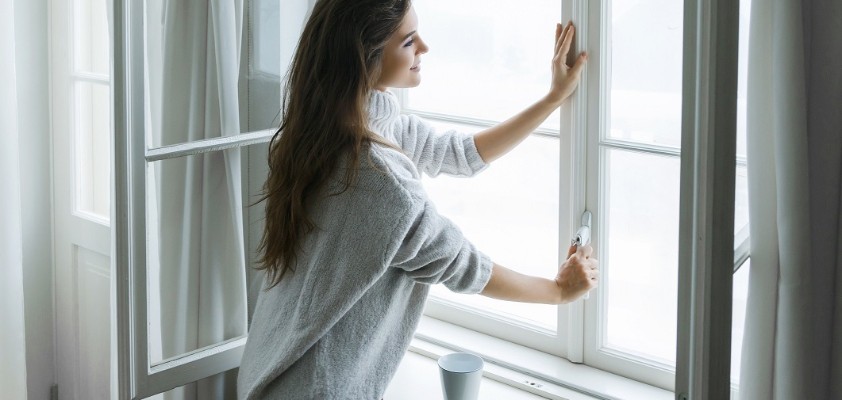 Eine Frau schließt ein Fenster von Innen.
