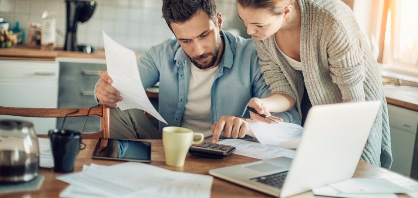 Ein Mann und eine Frau sind zusammen in der Küche und schauen auf Unterlagen.