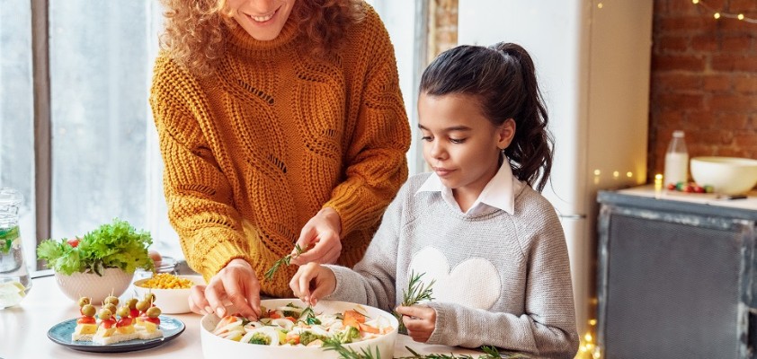 Eine Mutter macht  mit ihrer Tochter einen Auflauf in der Küche zusammen. 