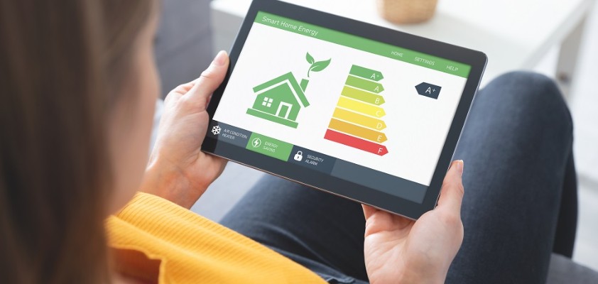 Eine Frau sitzt auf dem Sofa und schaut sich die Energieeffizienzklassen auf dem Tablet an.