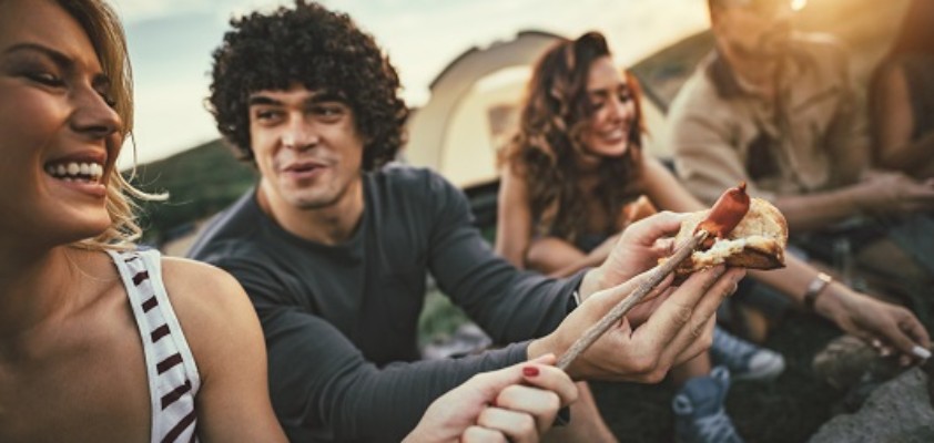 Mehrere Freunde sitzen zusammen und grillen
