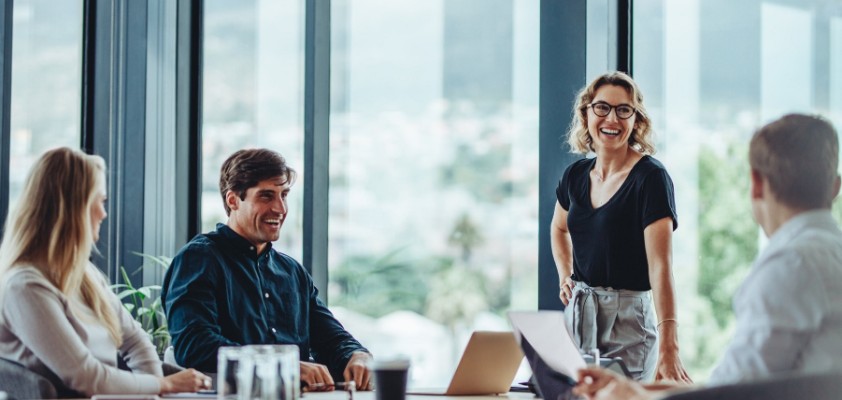 Ein vierköpfiges Team diskutiert in einem hellem Büro mit großen Fenstern