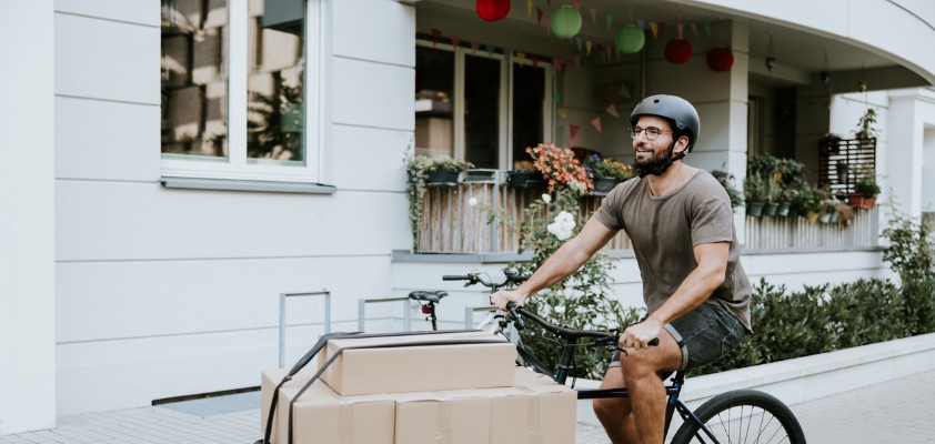 Ein junger Mann transportiert Kartons auf einem Lastenrad.